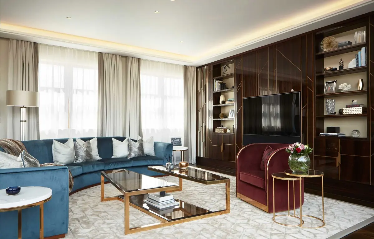 Living room with walnut wall panelling and inset shelving behind a blue sofa